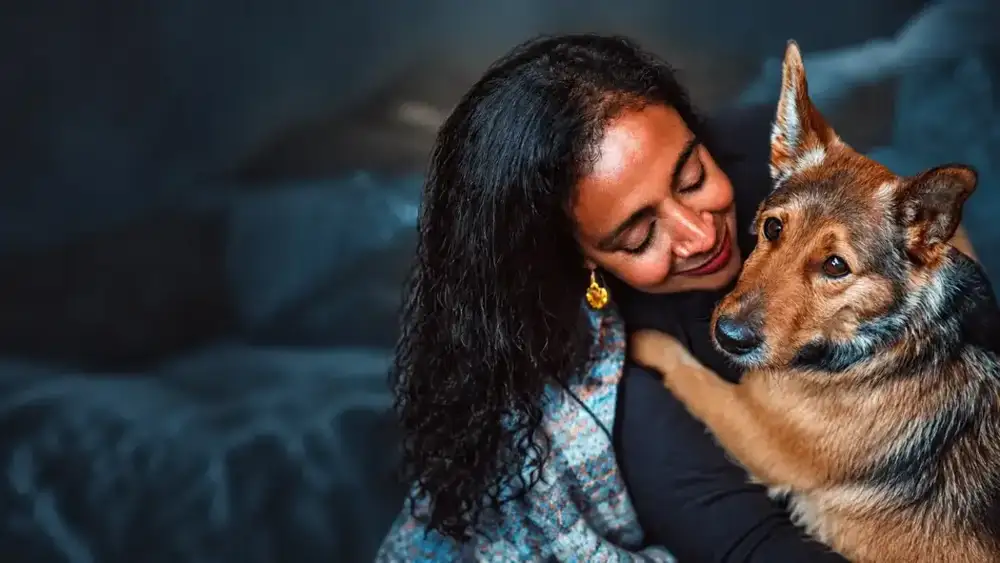 A woman smiles as she embraces a German shepherd